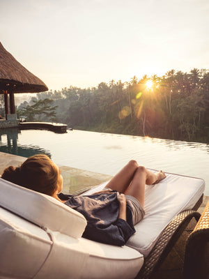 Girl by pool in the jungle with sunrise